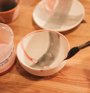 close-up-female-s-hand-painting-ceramic-bowl-with-paintbrush-1